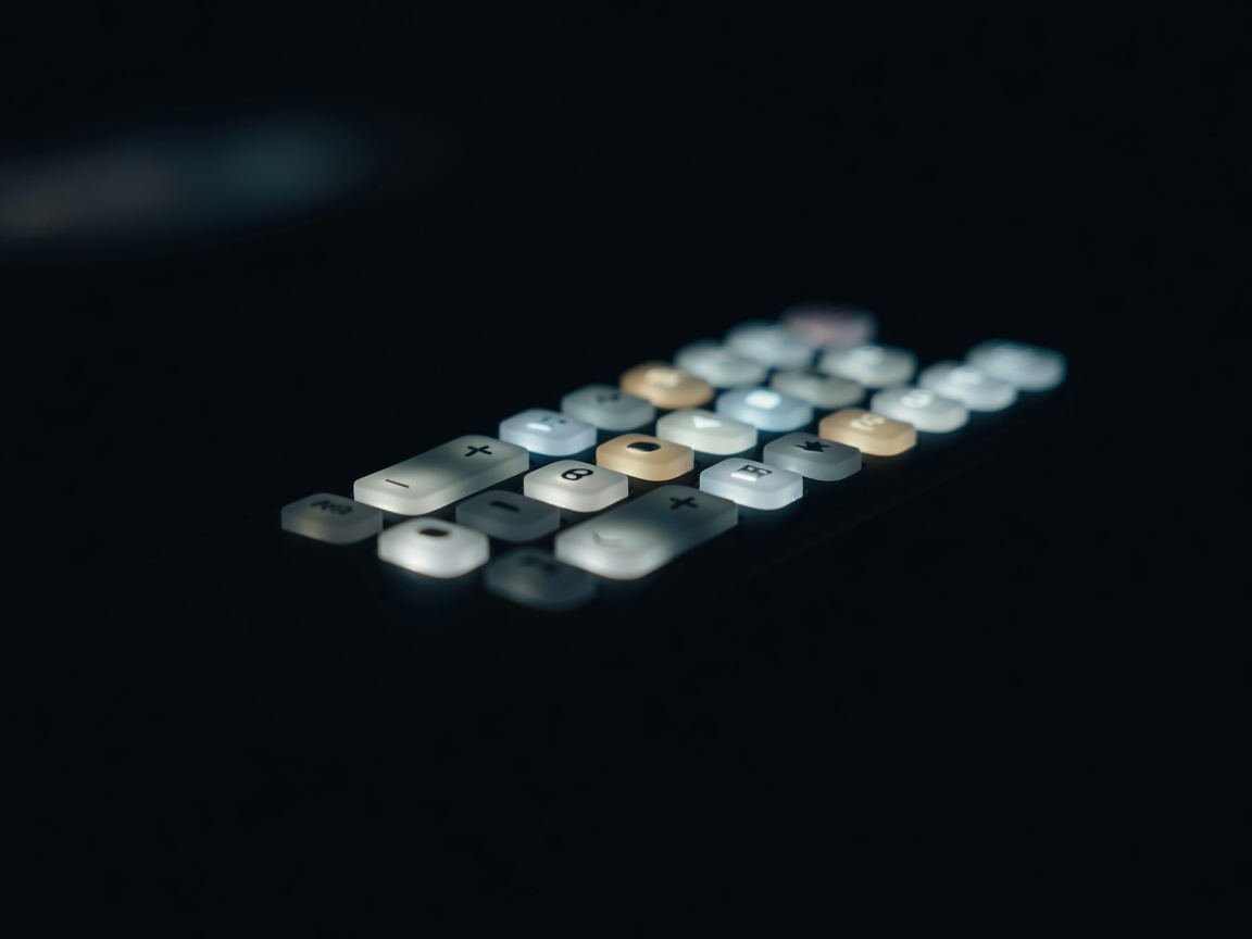 Backlit remote control buttons glowing in a dark room, macro close-up